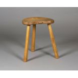 A Robert 'Mouseman' Thompson oak three-legged stool, the shaped seat raised on staked legs, carved