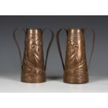 A pair of Arts and Crafts Newlyn copper twin-handled vases of conical form, the bodies worked with