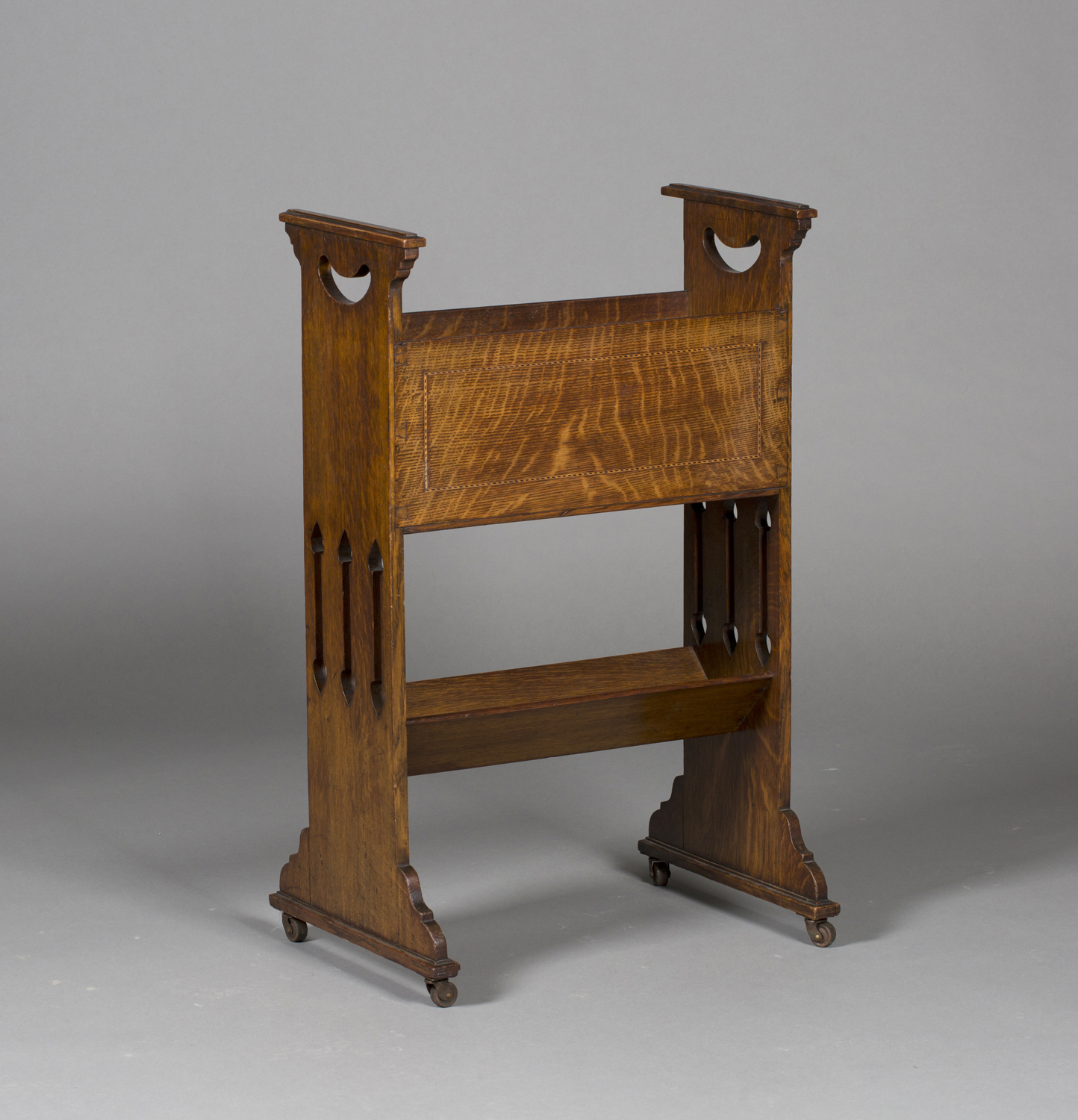 An Edwardian Arts and Crafts oak magazine/book rack, possibly Glasgow School, the shaped and pierced