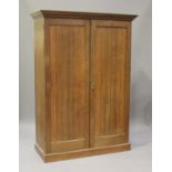 An Edwardian Arts and Crafts oak wardrobe, the dentil moulded pediment above a pair of panelled