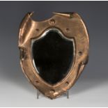 An early 20th century Arts and Crafts copper wall mirror of shield form, the bevelled glass within a