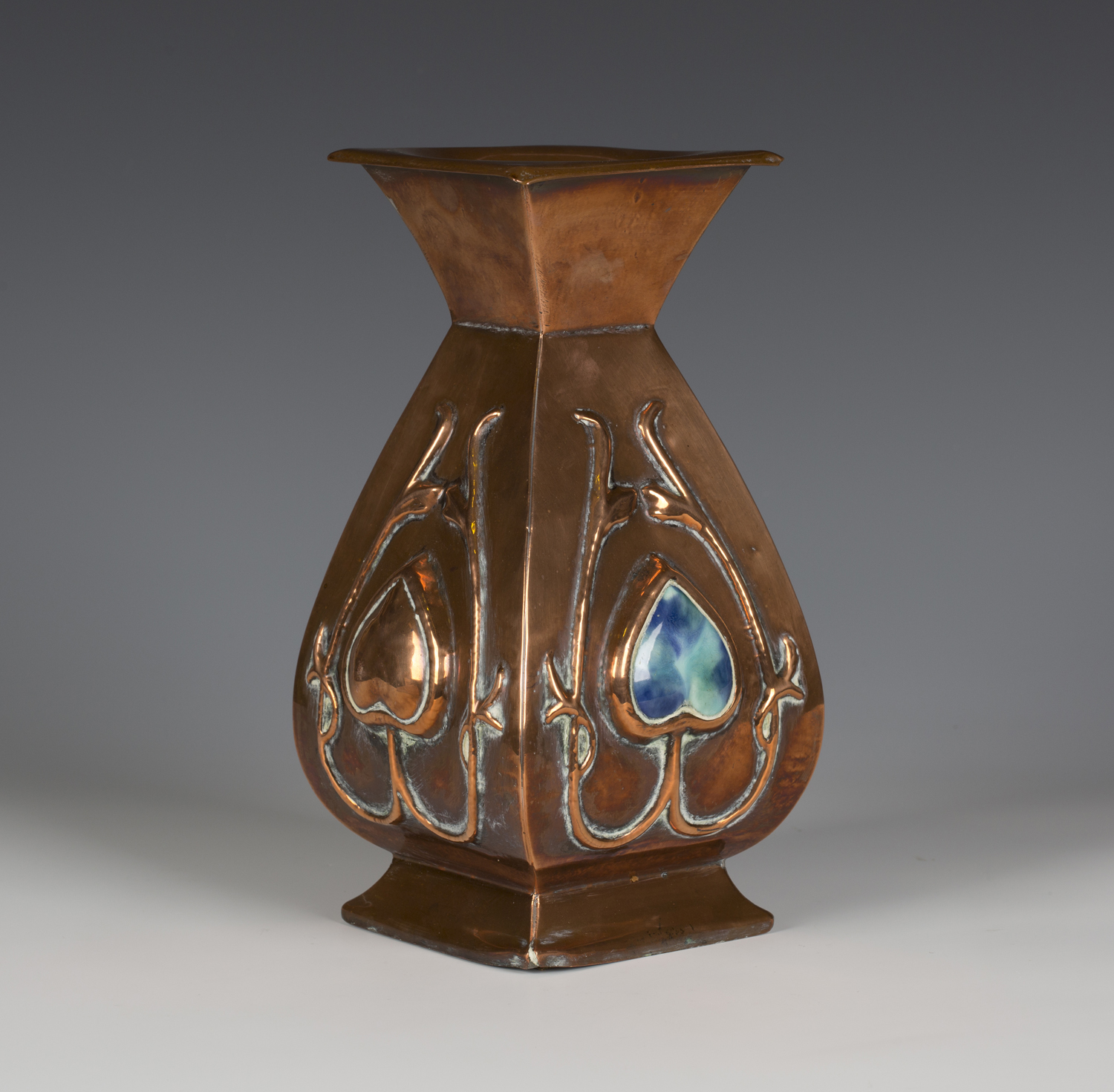 An Arts and Crafts copper vase of square section baluster form, the body worked with stylized