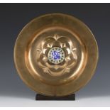 A late 19th century Arts and Crafts patinated copper alms dish, the centre with an enamelled