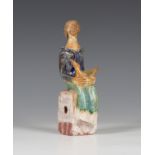 A Shelagh Spear studio pottery figure, modelled as a lady seated on a rectangular base, a bird