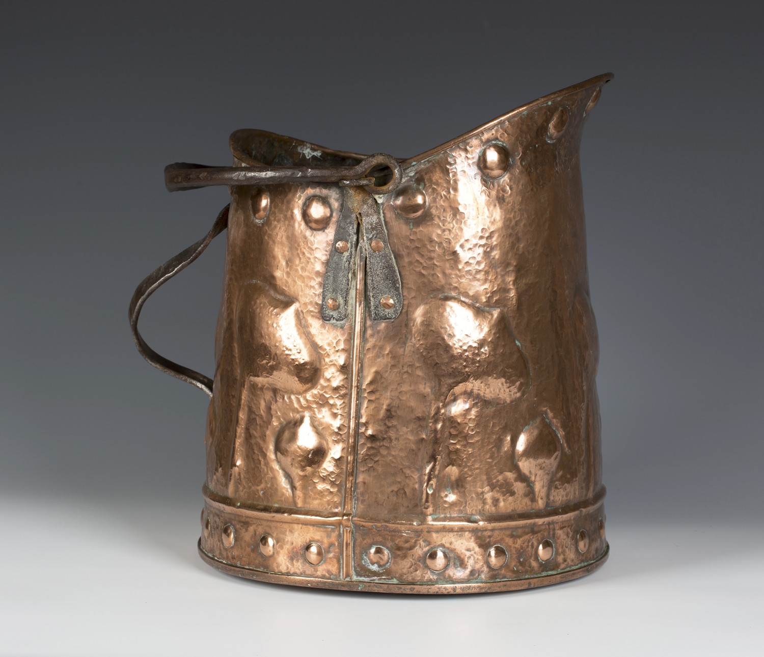 An Arts and Crafts polished copper coal bucket with applied wrought iron handles, the hammered