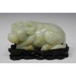 A Chinese pale celadon jade carving of an ox, modelled in a recumbent pose with head turned to its