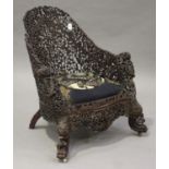 A 19th century Burmese carved hardwood tub back armchair, profusely pierced with overall foliage and