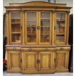 An early 20th century oak breakfront bookcase cabinet, the arched frieze back panel above a dentil