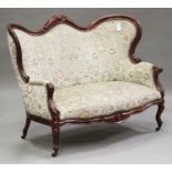 A late 19th century mahogany showframe settee with carved decoration, upholstered in green floral