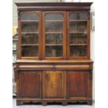 A mid-Victorian mahogany bookcase cabinet, the moulded pediment above three arch glazed doors, the