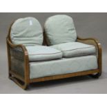 An Art Deco walnut framed three-piece bergère suite, the arched backs above removable cushions, on