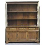 An 18th century and later oak dresser, the shelf back above three frieze drawers with brass plate