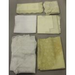 A small group of textiles, including an ivory-toned linen tablecloth with cellular lacework
