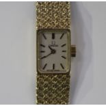 An Omega 9ct gold lady's bracelet wristwatch, the signed rectangular silvered dial with black