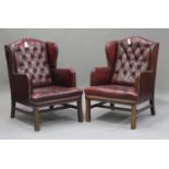 A pair of late 20th century claret buttoned leather wingback armchairs with brass studwork