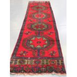 A Turkish runner, early/mid-20th century, the deep red field with a column of four linked