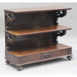 A mid-Victorian mahogany three-tier serving buffet, the moulded shelves raised on carved scroll