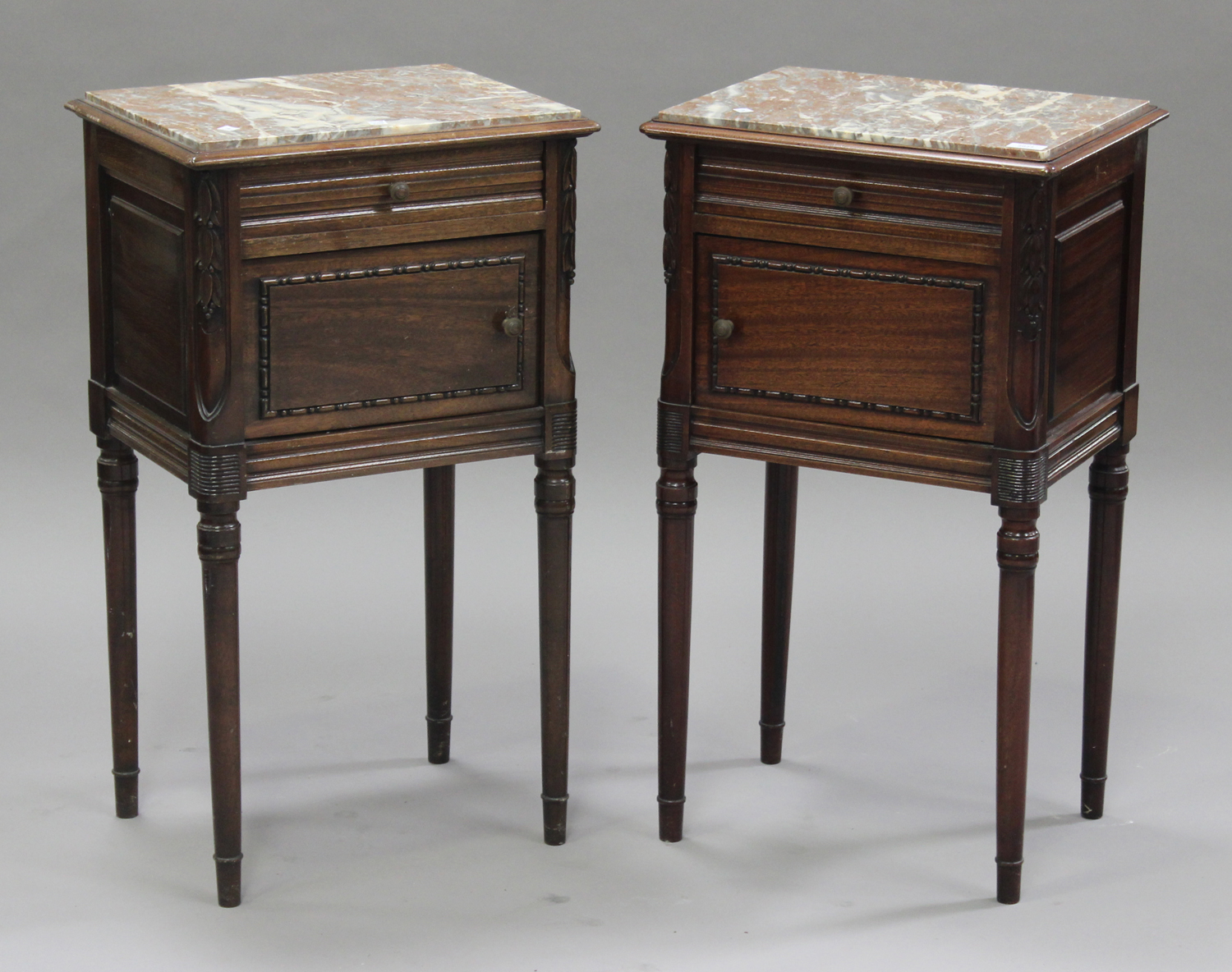 A pair of 20th century French mahogany bedside cupboards, each inset with a marble top above a