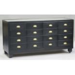 An early/mid-20th century black painted haberdashery shop counter, fitted with sixteen drawers,