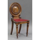 A Victorian oak hall chair with carved decoration, the round panel back above a red leatherette