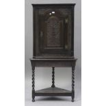 A 19th century oak corner cabinet-on-stand, the arched panel door carved with ascending flowers, the