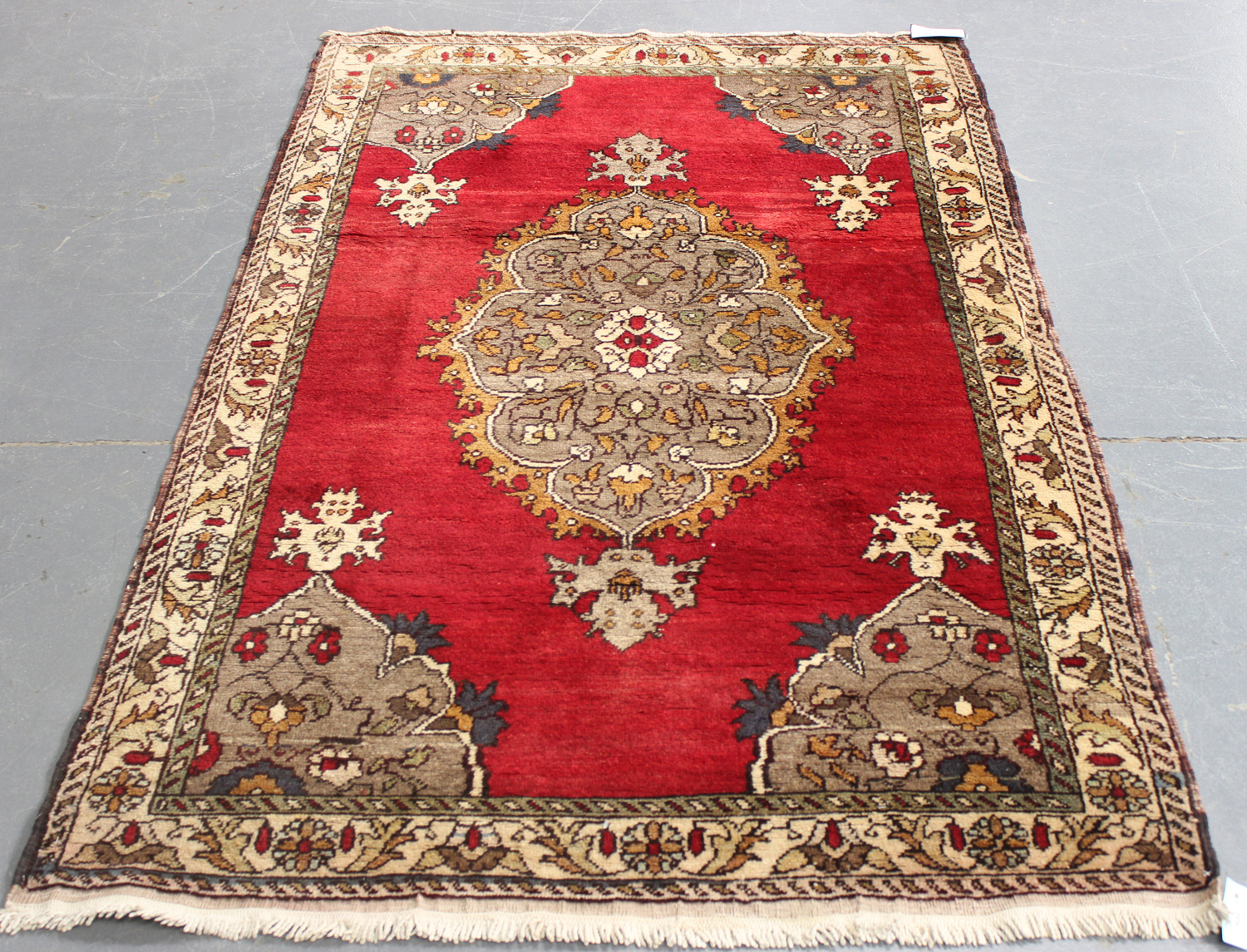 A Turkish rug, mid-20th century, the red field with a lobed medallion and shaped spandrels, within