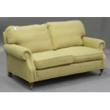 A modern two seat sofa, upholstered in faded golden fabric, raised on turned oak legs and brass