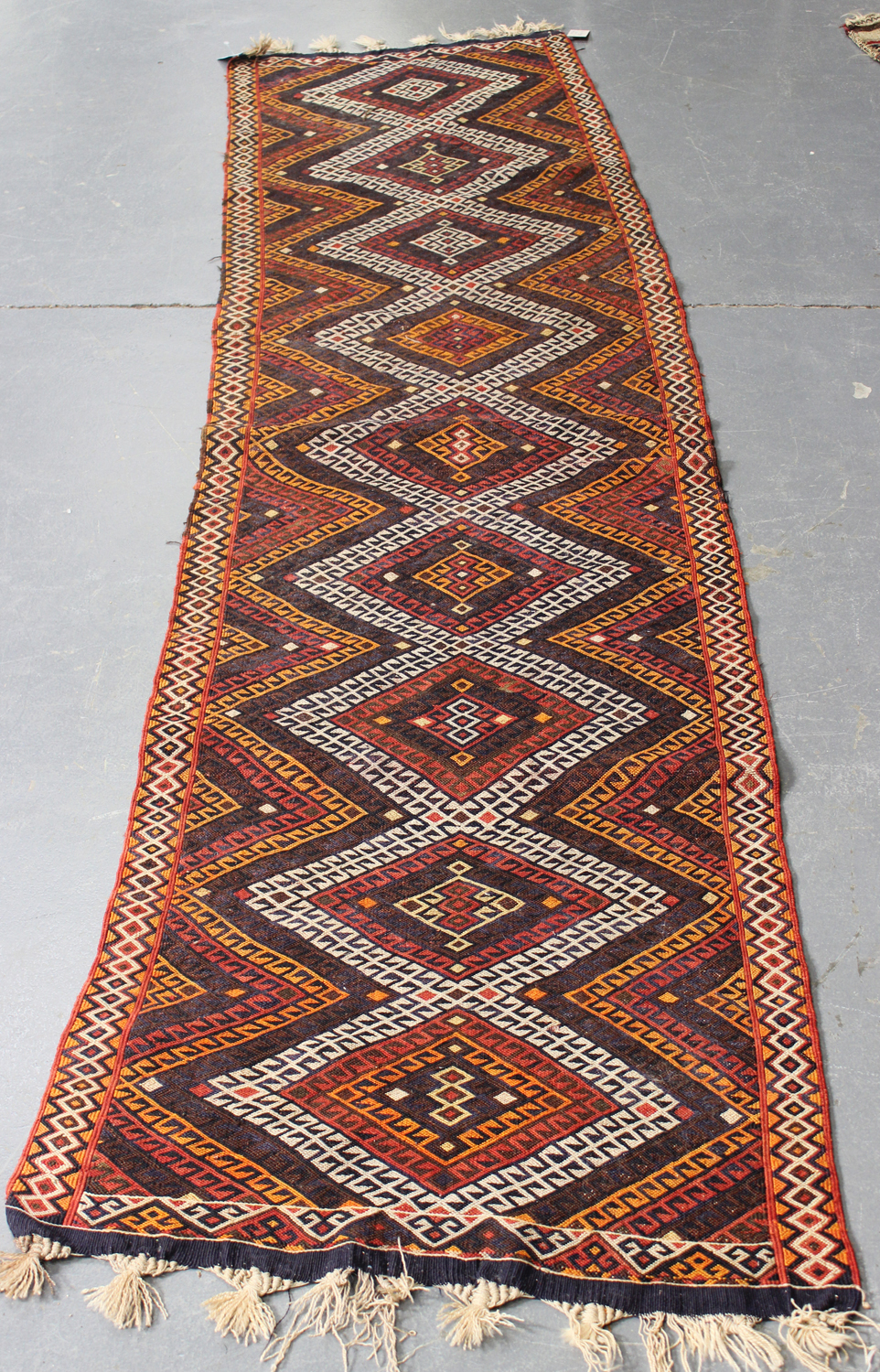 A Turkish flatweave runner, late 20th century, the polychrome field with a single column of hooked