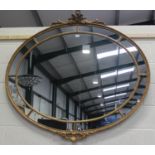 A large 20th century gilt framed oval sectional wall mirror with ribbon and scroll surmount, 135cm x