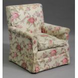 An early 20th century armchair, covered in a floral printed fabric, raised on oak tapering legs