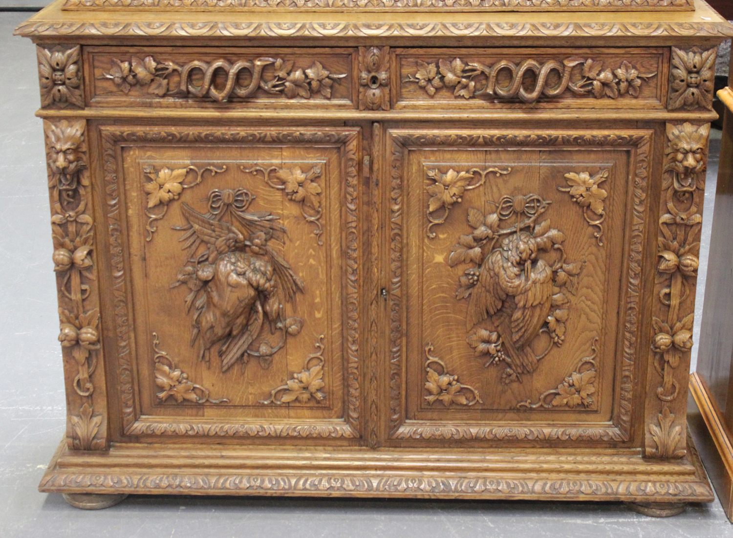 A mid-Victorian oak bookcase cabinet, profusely carved with floral scrolls and masks, the moulded - Image 2 of 4