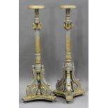 A pair of 20th century grey and gilt painted carved wooden torchères, the circular tops raised on