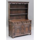 A 20th century Jacobean Revival oak dresser with carved decoration, the shelf back above two