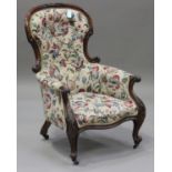 A Victorian mahogany salon armchair with carved decoration, upholstered in floral fabric, raised
