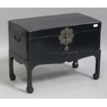 A 20th century Chinese black painted softwood trunk with metal mounts, raised on shaped block