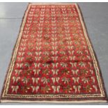 A Turkish rug, mid-20th century, the red field with an unusual design of overall flowerheads and
