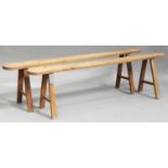 A pair of early 20th century cherry benches, the curve-ended tops on splayed legs united by