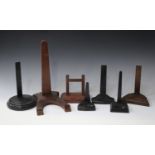 A large collection of mainly early 20th century ebonized plate display stands, together with oak and