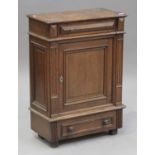 A 20th century French oak side cabinet, the hinged top and frieze drawer above a panelled door and a