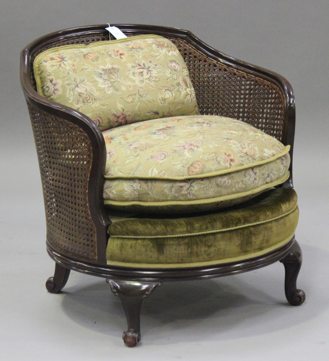 A George V mahogany bergère armchair, the cane back and sides above a loose cushion, on cabriole