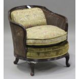 A George V mahogany bergère armchair, the cane back and sides above a loose cushion, on cabriole