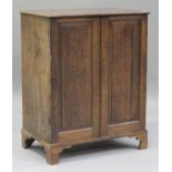 A George III oak press cupboard, fitted with a pair of panelled doors revealing sliding trays, on