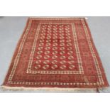 An Afghan rug, early 20th century, the claret field with overall guls, within a complimentary