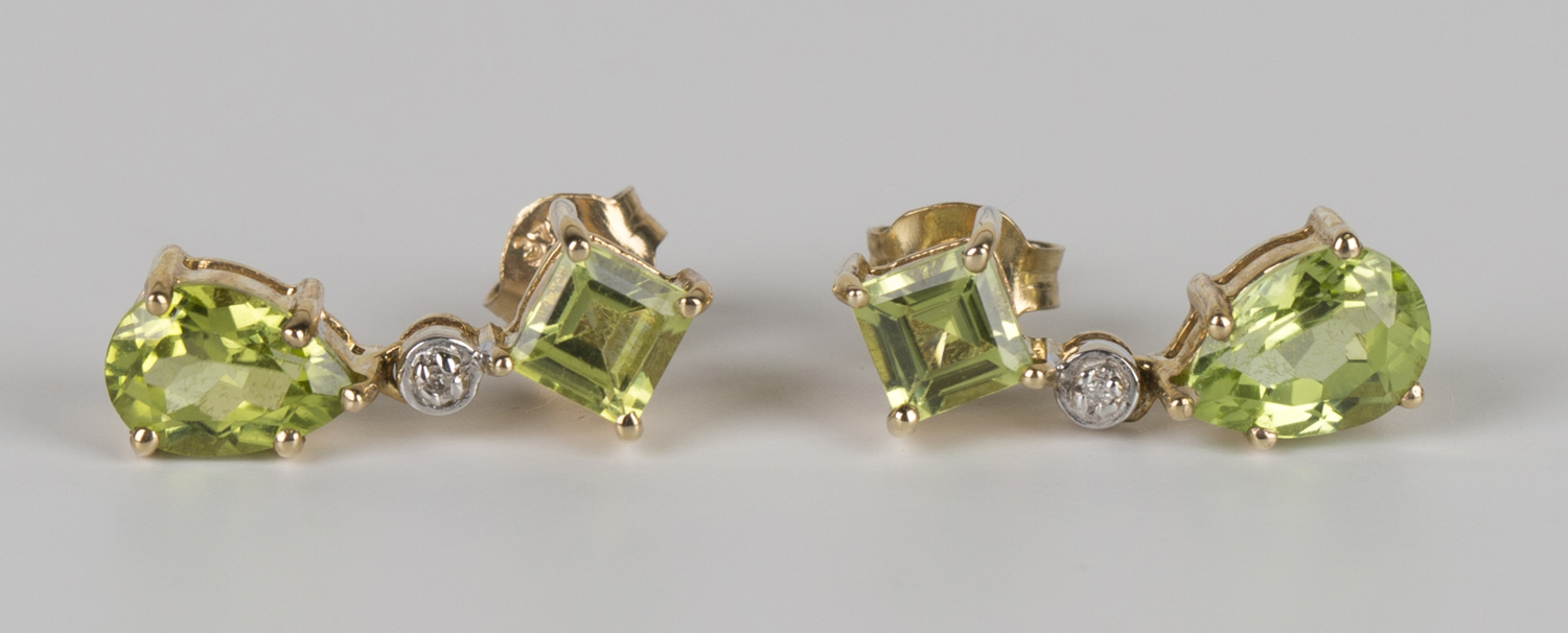 A pair of gold, peridot and diamond pendant earrings, each claw set with a pear shaped peridot