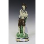 A pearlware figure of Simon, circa 1800, modelled as a boy standing with his arms folded, leaning