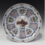 A Dutch Delft polychrome charger dish, mid-18th century, painted to the centre with a basket