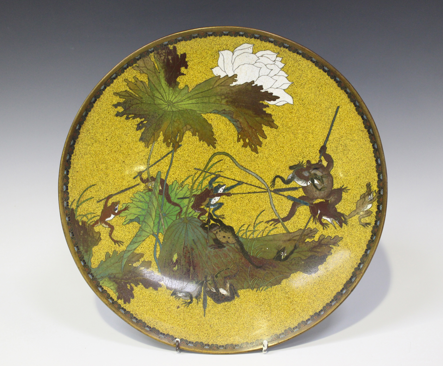 A Japanese cloisonné circular dish, Meiji period, decorated with battling frogs and toads using