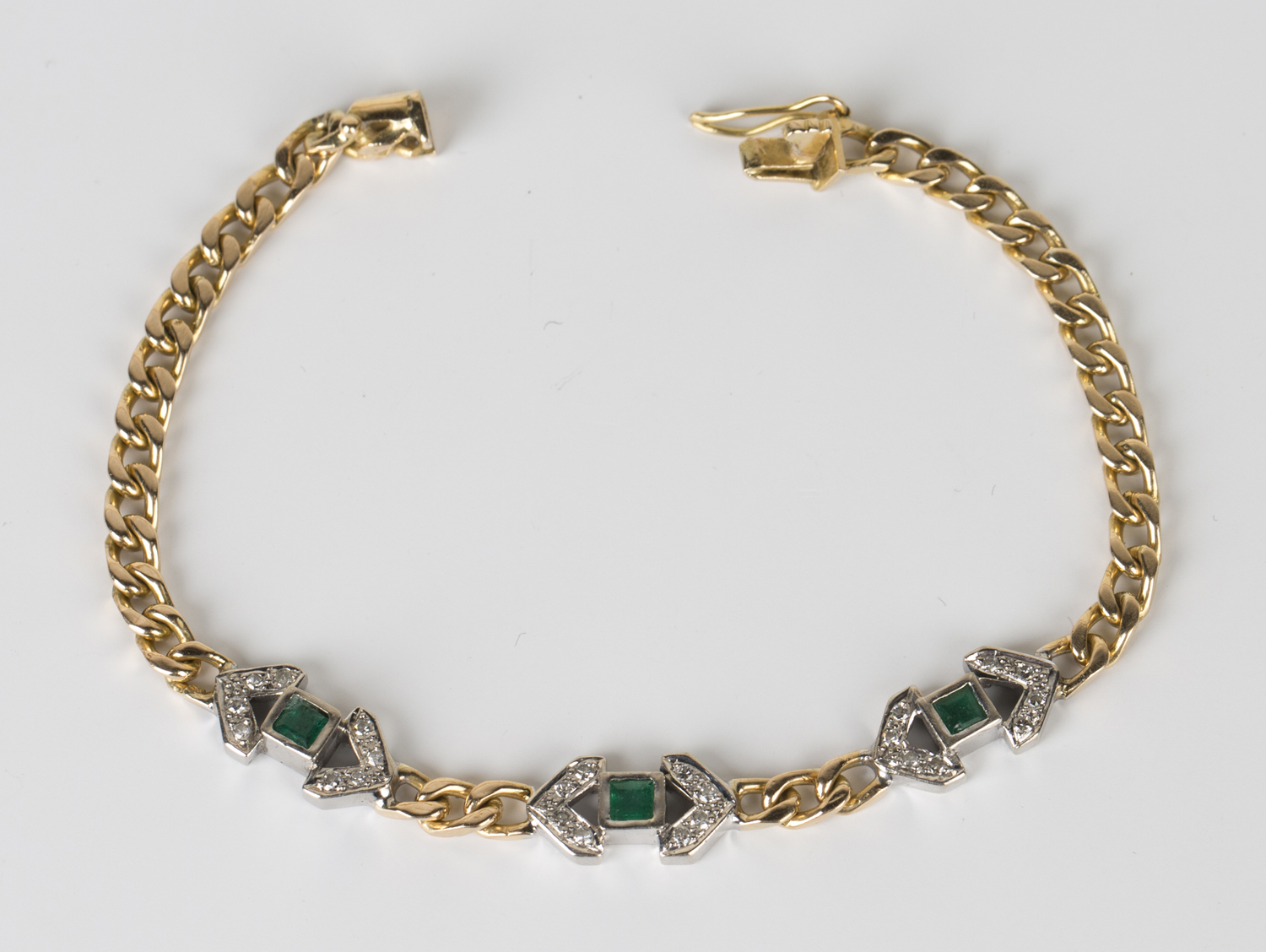 A gold, emerald and diamond bracelet in a faceted curblink design, the front mounted with three