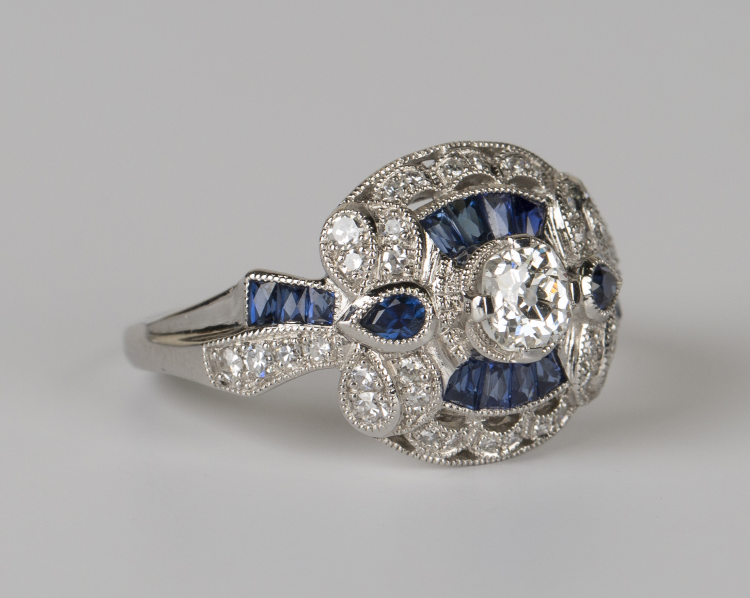 A platinum, sapphire and diamond ring, collet set with the principal circular cut diamond within a