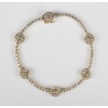 A gold and diamond bracelet, designed as a row of claw set circular cut diamonds with six diamond